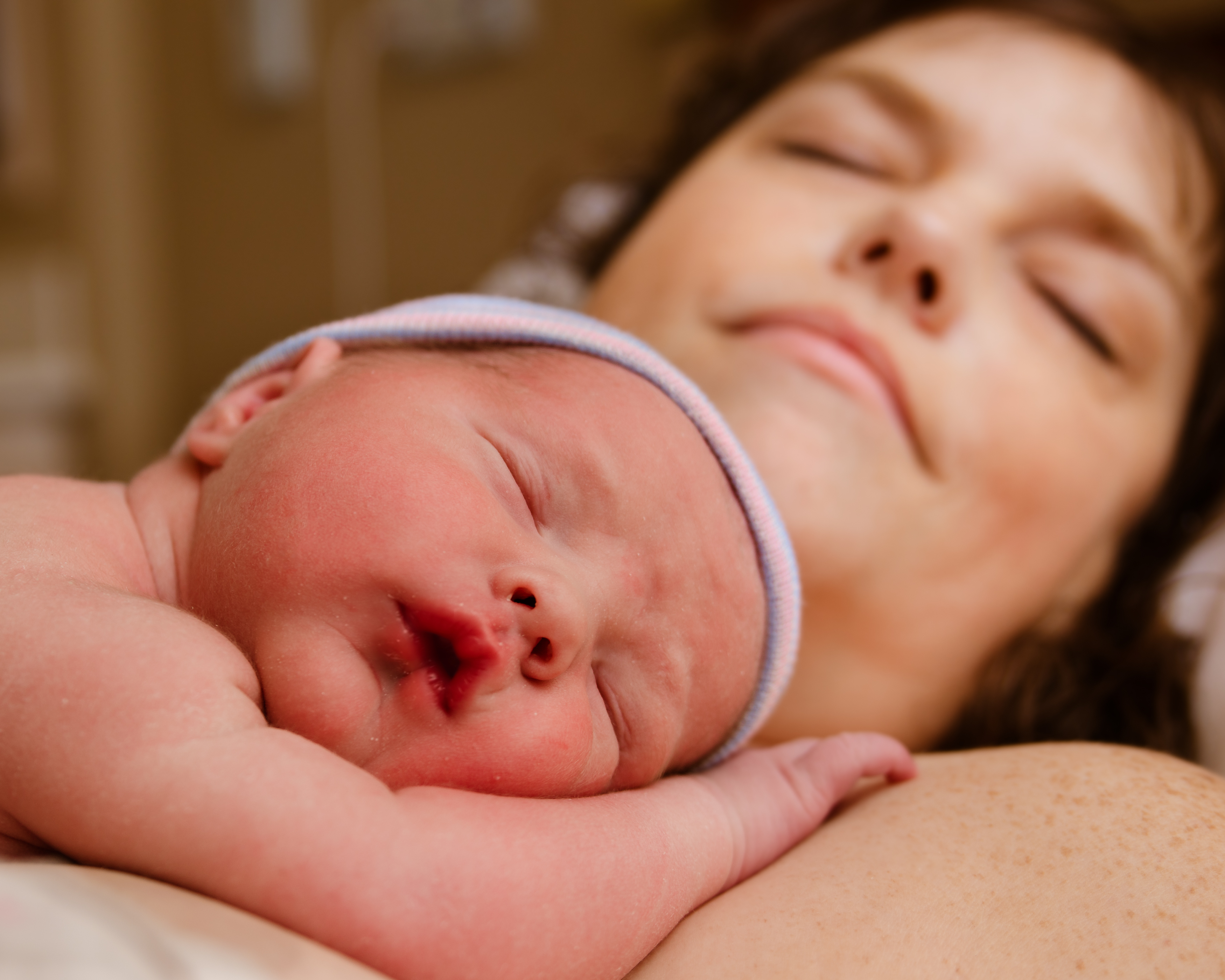 Portrait of infant resting on mother after childbirth
